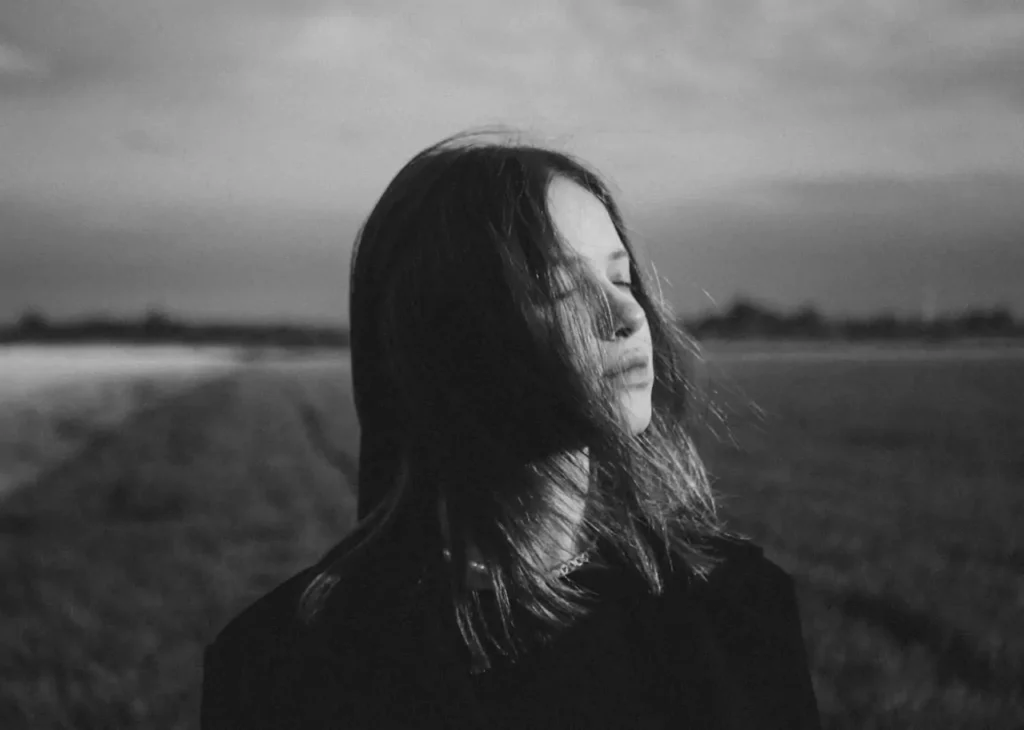 Black and white photo of a woman with closed eyes reflecting on harsh truths about life and people