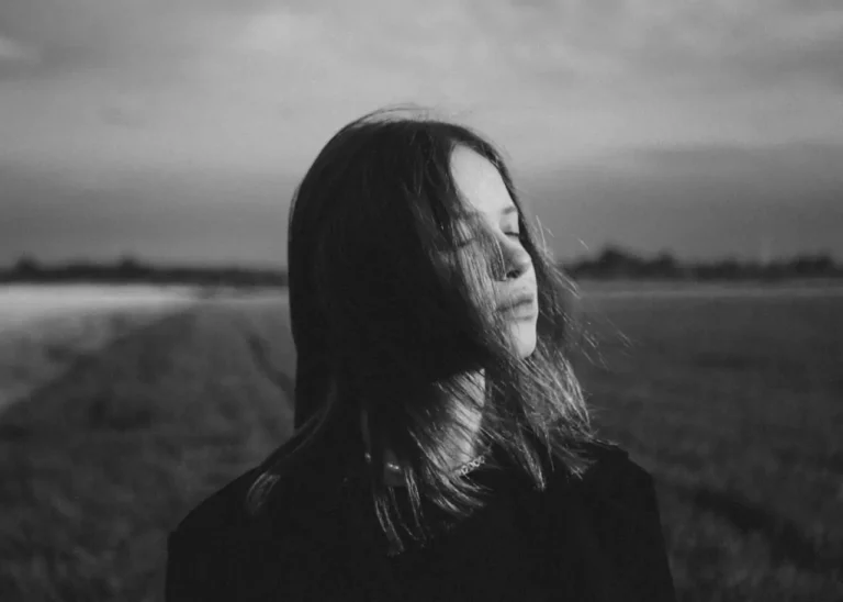 Black and white photo of a woman with closed eyes reflecting on harsh truths about life and people