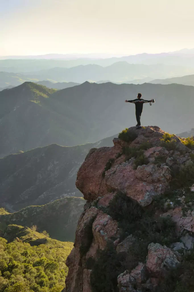 A man on top of a mountain reflecting on life harsh quotes