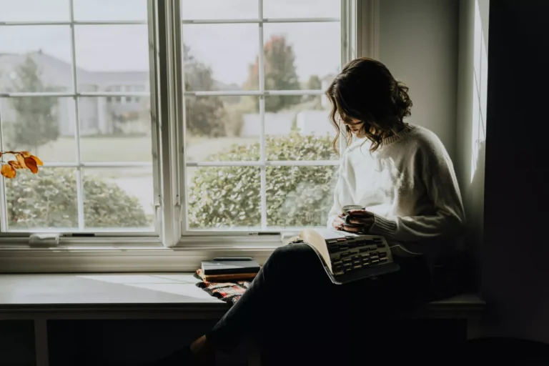 A woman in solitude reading in a nice room by the window